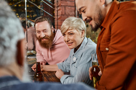 smiling multicultural workmates listening to blurred colleague while planning new project in pub