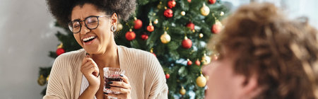 young jolly african american woman holding wine glass and laughing sincerely, Christmas, bannerの写真素材