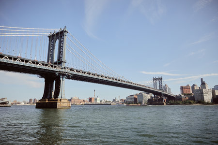 scenic view of manhattan bridge under blue sky over east river with new york urban landscape