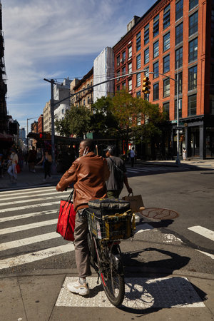 NEW YORK, USA - NOVEMBER 26, 2022: african american cyclist waiting on crossroad with traffic lightsのeditorial素材