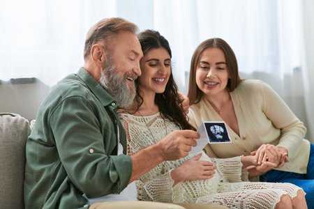 jolly pregnant daughter showing her father and her cheerful partner ultrasound of baby, ivf concept