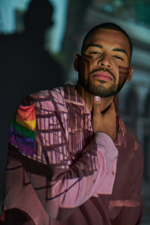 stylish bearded african american man looking at camera in digital projector lights, fashion conceptの写真素材