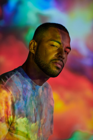 portrait of handsome man looking at camera in colourful digital projector lights, fashion conceptの写真素材