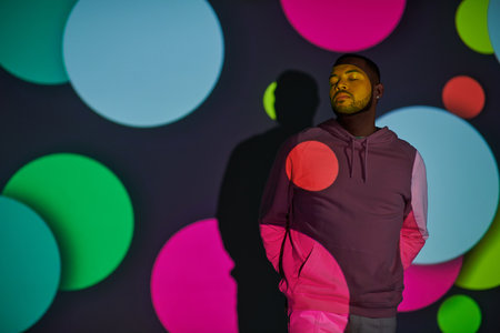 handsome man with hands behind back and closed eyes in digital projector lights, fashion concept