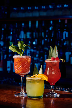 three refreshing cocktails with fruit and plant decorations with bar on background, conceptの写真素材