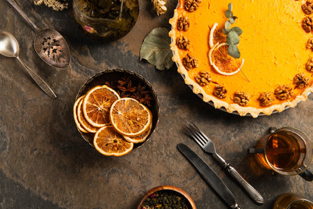 thanksgiving backdrop with delicious pumpkin pie, vintage cutlery and orange slices on stone tableの写真素材