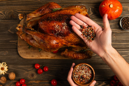 cropped view of man with wooden bowl and spices near thanksgiving turkey, festive dinner preparationの写真素材