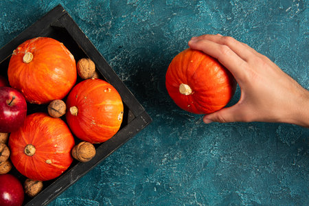 cropped view of man holding ripe pumpkin near tray with seasonal harvest, thanksgiving conceptの写真素材