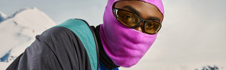 handsome young man in pink balaclava with sunglasses with snowy backdrop, winter concept, bannerの写真素材