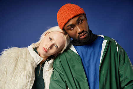 stylish multiethnic couple in winter attire, young woman in faux fur jacket and african american man