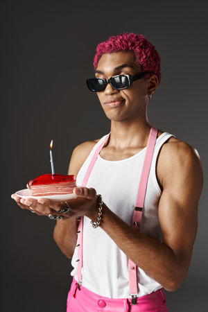 handsome african american man in sunglasses posing with cake and burning candle, fashion conceptの写真素材