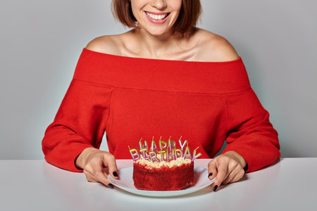 brunette woman in red attire holding piece of bento cake on grey background, Happy Birthday