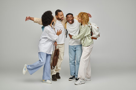 joyful students in casual urban wear with backpacks posing and hugging happily, studying conceptの写真素材