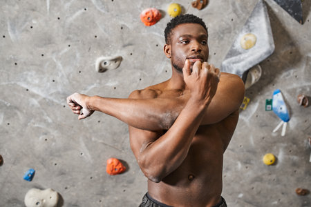 strong handsome african american man posing topless and stretching his arms in front of cameraの写真素材