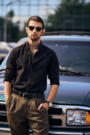 appealing elegant male model in black stylish shirt with hands in pockets looking at camera, fashionの写真素材
