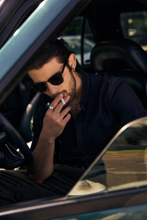vertical shot of appealing sexy man posing with cigarette behind driving steering wheel, styleの写真素材