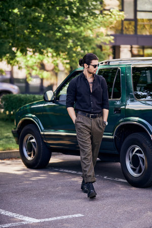 handsome sexy man with sunglasses in black shirt walking near his car and looking away, fashionの写真素材