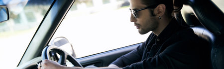appealing man with accessories in black attire behind steering wheel of his car, sexy driver, banner