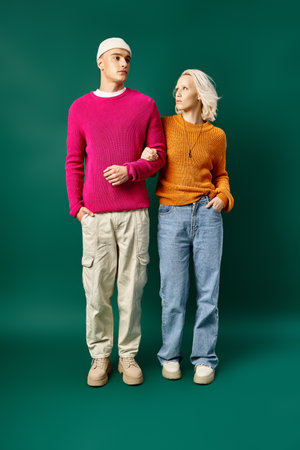 fashionable man and woman in winter outfits posing with hands in pockets on turquoise backgroundの写真素材