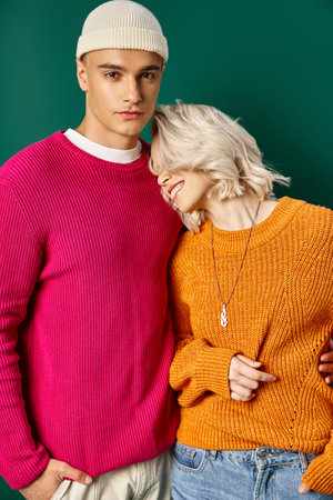 happy blonde woman leaning on handsome boyfriend in sweater on turquoise background, young coupleの写真素材