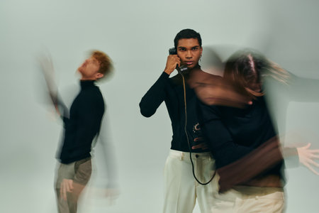 young african american man posing with landline phone with other male models moving, long exposureの写真素材