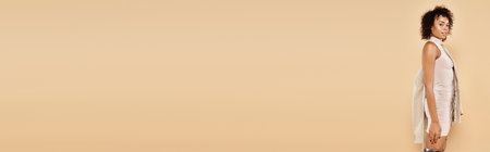 autumn banner, beautiful african american woman posing in tight dress with blazer on beige backdropの写真素材