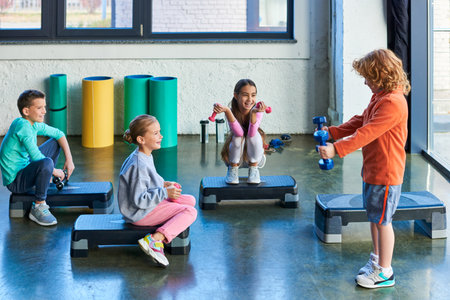 preadolescent happy children on fitness steppers with dumbbells smiling joyfully, child sportの写真素材