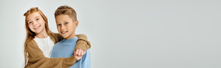 little children in casual attires hugging and smiling at camera on gray backdrop, fashion, bannerの写真素材