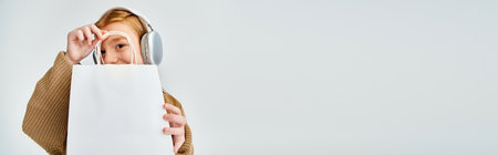 jolly little girl with headset and present bag in front of her face, fashion concept, bannerの写真素材