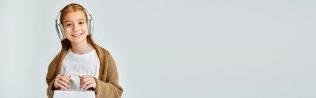 happy little girl with headset holding present bag and smiling at camera, fashion concept, banner