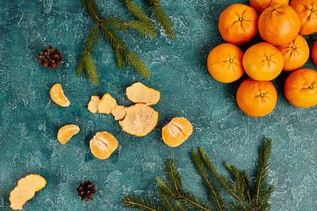 fresh mandarins and pine cones with fir branches on blue rustic backdrop, Christmas theme, top viewの写真素材