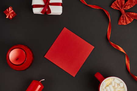 red envelope near hot chocolate with marshmallows and red decorative ribbons on black, Christmasの写真素材