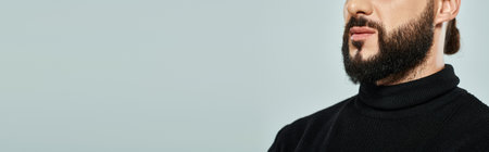cropped view of masculine and bearded arabic man in black turtleneck on grey backdrop, bannerの写真素材