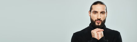 portrait of bearded arabic man in black turtleneck looking at camera on grey backdrop, bannerの写真素材