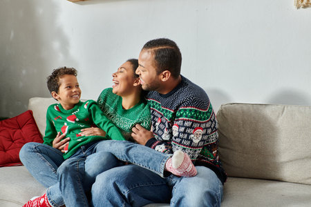 joyous african american parents holding their son on laps smiling happily at each other, Christmasの写真素材