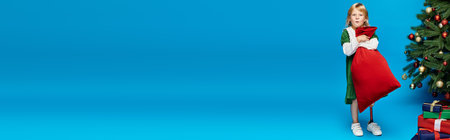 amazed girl in dress with prosthetic leg holding sack bag with presents near Christmas tree, bannerの写真素材