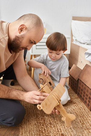vertical shot of bearded modern father spending time with his little son playing wooden toysの写真素材