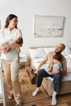 vertical shot of modern parents smiling happily at each other while spending time with children