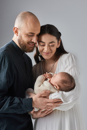 vertical shot of loving young parents holding their newborn baby boy and smiling happily, familyの写真素材