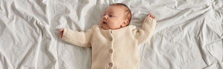top view of adorable newborn baby boy in lying on bed at home with slightly raised arms, banner