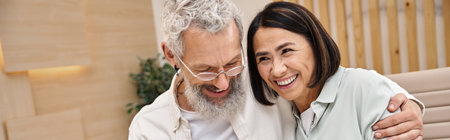 happy bearded man hugging multiracial wife while purchasing new house in real estate office, banner
