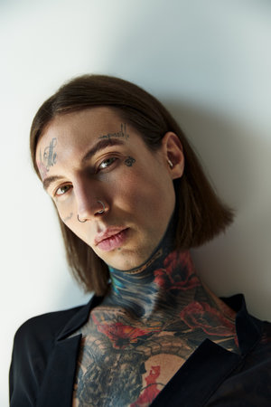 portrait of sexy alluring male model in transparent black blouse with tattoos looking at camera