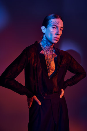 alluring young man with tattoos in transparent shirt posing with hands on hips, fashion conceptの写真素材