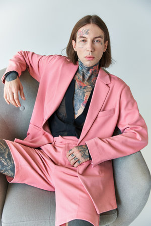 stylish sexy man in pink blazer and shorts sitting on chair looking at camera, fashion conceptの写真素材