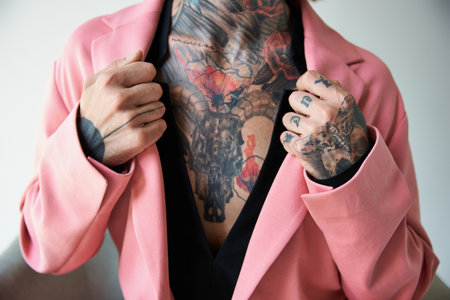 cropped view of young man with tattoos with hands on collar of his stylish pink blazer, fashionの写真素材
