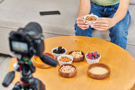 cropped view of video blogger with walnuts near various vegetarian ingredients and digital cameraの写真素材