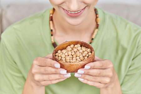 cropped view of happy vegetarian woman with wooden bowl of chickpeas, nutritious vegetarian dietの写真素材
