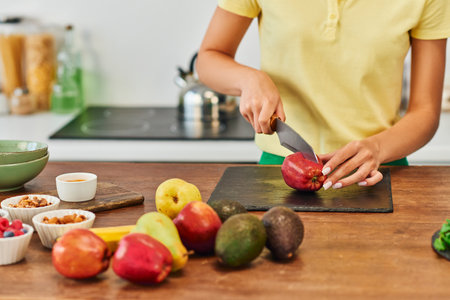 cropped woman cutting apple near fresh fruits and various plant origin ingredients, plant-based dietの写真素材