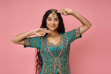 attractive young indian female model in national costume gesturing while dancing on pink backgroundの写真素材