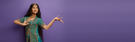 cheerful indian woman in traditional clothing gesturing while dancing on purple backdrop, bannerの写真素材